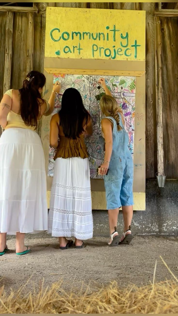 Mujeres de espaldas pintando un mural comunitario
